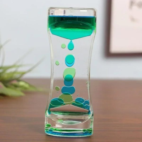 Ampulheta de óleo líquido com cores verdes e azuis, mostrando o fluxo de óleo de cima para baixo em um recipiente de vidro.
