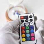 Controle remoto com botões coloridos e funções de luz, incluindo ON, OFF, brilho e cores RGB, usado para controlar uma lâmpada de plasma luminosa.