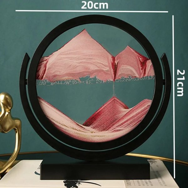 Paisagem montanhosa com picos e vales, vista através de um quadro circular de 20cm de diâmetro, com detalhes em tons de rosa e azul, apoiado numa base preta.
