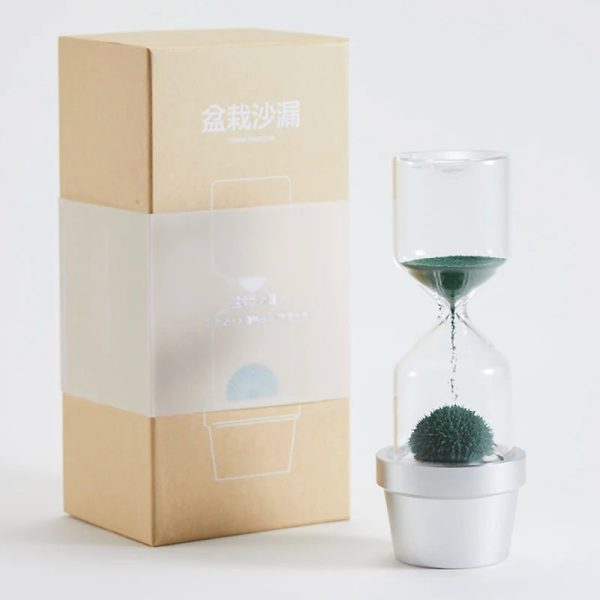 Ampulheta moderna com planta de cacto em vaso branco, com embalagem de papelão ao lado, vista frontal, fundo branco.