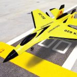 Foguete de treino militar amarelo com detalhes em preto e marcas da força aérea chinesa, colocado numa pista de decolagem.