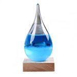 Lâmpada de plasma com líquido azul em forma de gota, colocada sobre base de madeira, com efeito de luz e brilho.