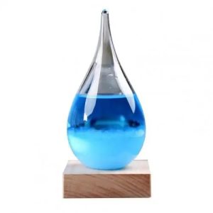 Lâmpada de plasma com líquido azul em forma de gota, colocada sobre base de madeira, com efeito de luz e brilho.