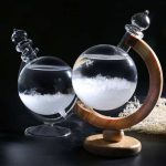 Reagente de cristal com suporte de madeira, contendo líquido transparente e cristais brancos no fundo, com fundo escuro.