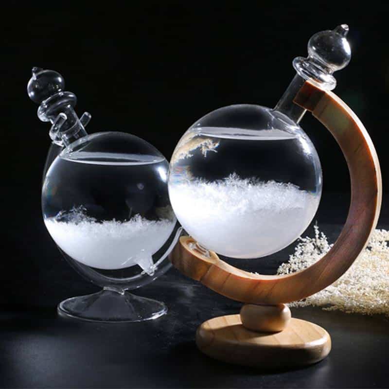 Reagente de cristal com suporte de madeira, contendo líquido transparente e cristais brancos no fundo, com fundo escuro.