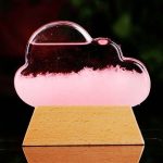 Lâmpada de plasma em forma de nuvem com efeito de luz rosa, colocada sobre base de madeira, mostrando o funcionamento interno e o efeito de plasma.