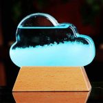 Lâmpada de plasma em forma de nuvem com luz azul, colocada sobre base de madeira, mostrando efeito de plasma visível na parte inferior.
