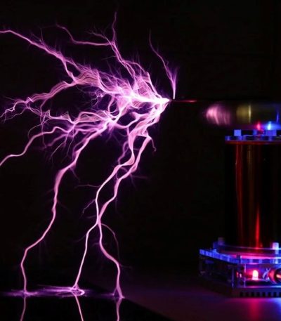Descarga de plasma azul e roxa de uma bobina de Tesla, com faíscas elétricas visíveis no ar escuro.