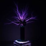 Descarga elétrica visível com raios violetas a partir de uma bobina de Tesla em ambiente escuro.