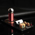 Bobina de Tesla mini com esfera metálica, componentes eletrónicos e bobinas de cobre, sobre fundo preto, mostrando detalhes do circuito e funcionamento.