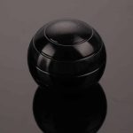 Bola giroscópio preta com superfície lisa e detalhes de linhas curvas, vista frontal, sobre fundo cinza.
