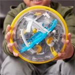 Bola de plástico transparente com componentes internos coloridos, incluindo pistas, obstáculos e peças de montagem, vista frontal com foco na estrutura interna.