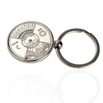 Chaveiro com calendário perpétuo, mostrando dias, meses, fases da lua e estações do ano, com detalhes em preto e branco.