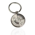 Chaveiro metálico com calendário perpétuo, fases da lua e indicador de estação do ano, visto de frente com detalhes visíveis.