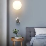 Candeeiro de parede com forma de astronauta a segurar uma luz redonda, decorativo e funcional para quarto infantil ou juvenil.