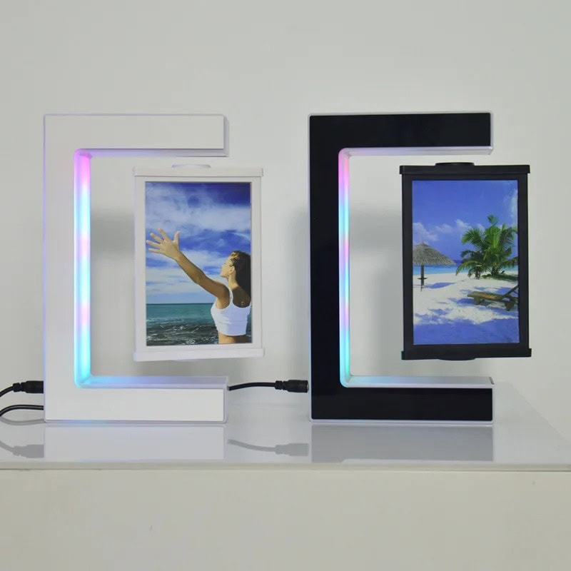 Candeeiro com Porta-Retratos em Levitação Dois candeeiros com porta-retratos em levitação, um branco e um preto, exibindo imagens de praia e natureza, com iluminação LED colorida ao redor.