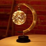 Lâmpada de plasma com forma de lua crescente, com filamentos de luz dentro de uma esfera de vidro, apoiada numa base preta.
