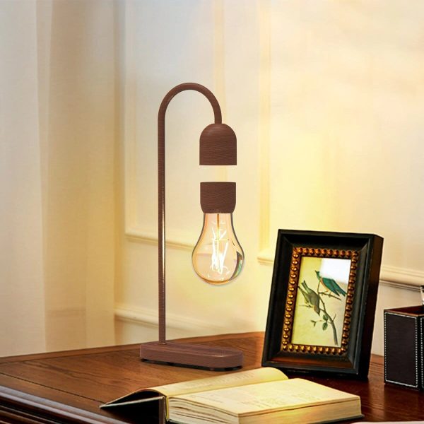 Candeeiro de mesa com lâmpada de filamento exposta, estrutura de madeira e design moderno, colocado numa mesa de madeira com quadro decorativo ao lado.