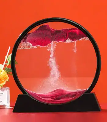 Lâmpada de areia rosa com base preta, mostrando a areia a cair dentro do vidro circular, fundo laranja vibrante.
