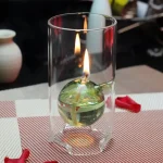 Candeeiro de mesa a óleo com chama acesa, esfera de vidro transparente, base de vidro, ambiente de loja de gadgets científicos, decoração de ciência.