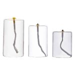 Três candeeiros de mesa a óleo em vidro de diferentes tamanhos, com pavios acesos, exibindo chamas pequenas e suaves.