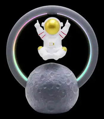 Miniatura de astronauta com capacete dourado, rodeado por anel de luz LED colorida, apoiado numa réplica da Lua com textura lunar detalhada.