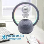 Candeeiro de mesa com figura de astronauta suspensa, anel de luz LED colorido e base que simula a Lua, com ligação Bluetooth 5.0.