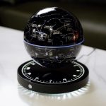 Candeeiro de presença em forma de esfera com mapa astronómico, mostrando constelações e estrelas, apoiado numa base circular iluminada.