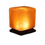 Candeeiro de sal do Himalaia em forma de cubo, iluminado, com base de madeira escura, destacando a textura e cor laranja do sal.