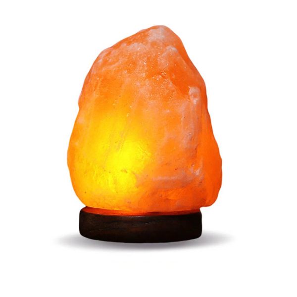 Candeeiro de sal do Himalaia com luz quente, forma irregular, sobre base de madeira escura, iluminação suave, destaque para textura cristalina.