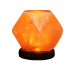 Candeeiro de sal em cristal hexagonal, iluminado, com base de madeira escura, destacando-se pela luz quente e translúcida.