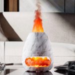 Difusor de óleo essencial em pedra de sal com vapor e luzes coloridas, colocado numa superfície de mesa moderna.