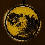 Globo terrestre dourado iluminado com luz de fundo, destacando os continentes e oceanos em detalhes.