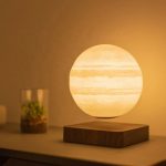 Candeeiro de mesa com design de Júpiter, esfera luminosa com faixas de nuvens, base de madeira escura, ambiente acolhedor, iluminação suave, decoração científica moderna.
