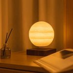 Lâmpada de mesa com design que imita o planeta Júpiter, com superfície texturizada e iluminação quente, colocada sobre uma base de madeira escura.