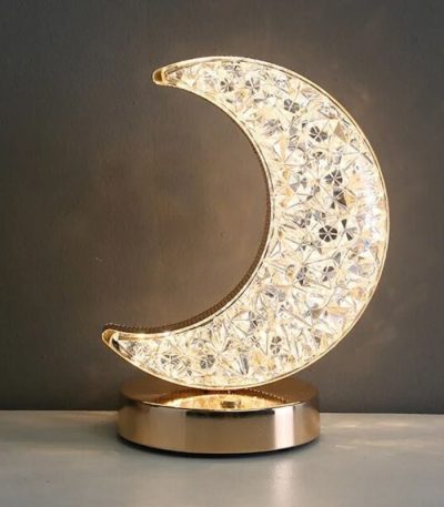 Luminária de lua em acrílico com detalhes brilhantes, base metálica dourada, iluminação suave, ideal para decoração de quarto ou sala.