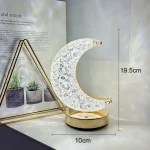 Luminária em forma de lua com detalhes cristalinos, base dourada, altura de 19,5cm e diâmetro de 10cm, decorativa para ambientes internos.