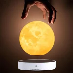 Mão a segurar uma réplica da Lua iluminada, suspensa acima de uma base de levitação.