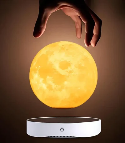 Mão a segurar uma réplica da Lua iluminada, suspensa acima de uma base de levitação.