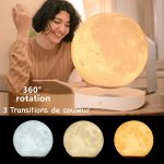 Mulher sorridente observa um candeeiro em forma de lua que levita, com mudança de cores, incluindo azul, verde e amarelo, em um ambiente interior.