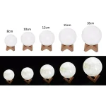 Vários tamanhos de lâmpadas de mesa em forma de esfera, com base de madeira, exibindo diferentes dimensões e iluminação.