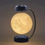 Candeeiro com forma de lua, iluminação amarelada, base e topo em preto, com braço curvo que conecta as partes, ideal para decoração de ciência.