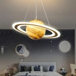 Lustre de teto com design de planeta com anéis, iluminação LED branca, suspenso por cabos finos, decorando um quarto com tema espacial.