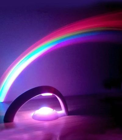 Projeção de arco-íris colorido a partir de um dispositivo de luz, refletindo no teto escuro, criando um efeito visual vibrante e educativo.