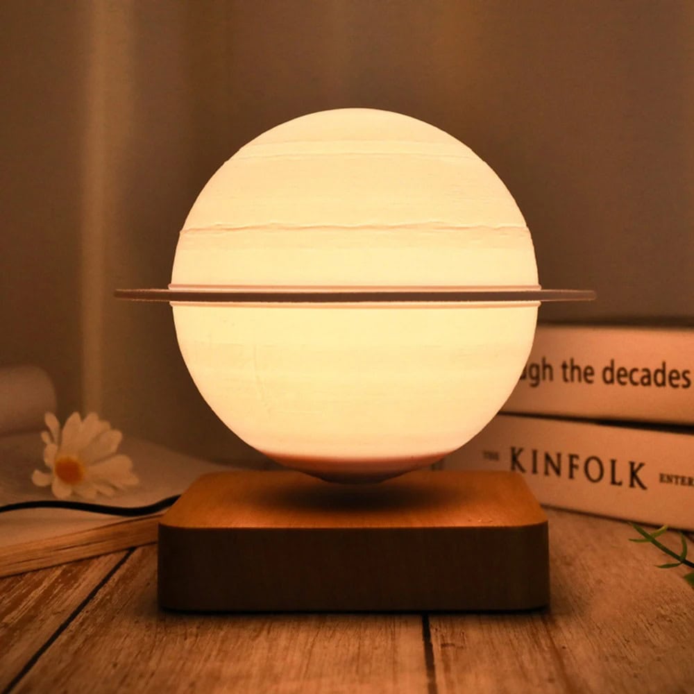 Candeeiro Saturno Magnético Candeeiro com forma de Saturno, com anel metálico ao redor, iluminado, sobre base de madeira, ambiente acolhedor.