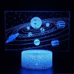 Lâmpada 3D com representação do Sistema Solar, planetas e órbitas em luz azul, base decorativa com padrão de rachaduras.