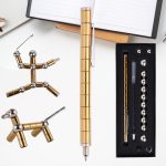 Conjunto de peças magnéticas de diferentes formas e tamanhos, incluindo uma caneta de escrita, numa mesa branca com caderno aberto e caixa de acessórios.
