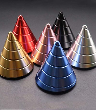 Cones giroscópicos metálicos em várias cores: dourado, vermelho, rosa, preto, azul e prateado, dispostos em círculo sobre fundo escuro.