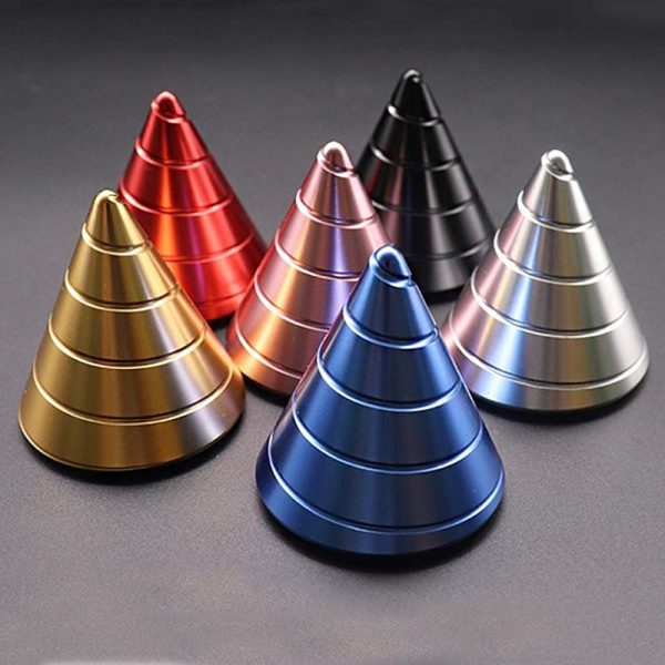 Cones giroscópicos metálicos em várias cores: dourado, vermelho, rosa, preto, azul e prateado, dispostos em círculo sobre fundo escuro.