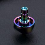 Cubo fidget silencioso com acabamento metálico iridescente, visto de cima, com detalhes coloridos e superfície lisa, colocado sobre fundo preto texturizado.